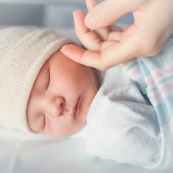 Baby sleeping with hand touching cheek