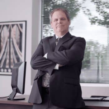 Man in suit in office with arms crossed