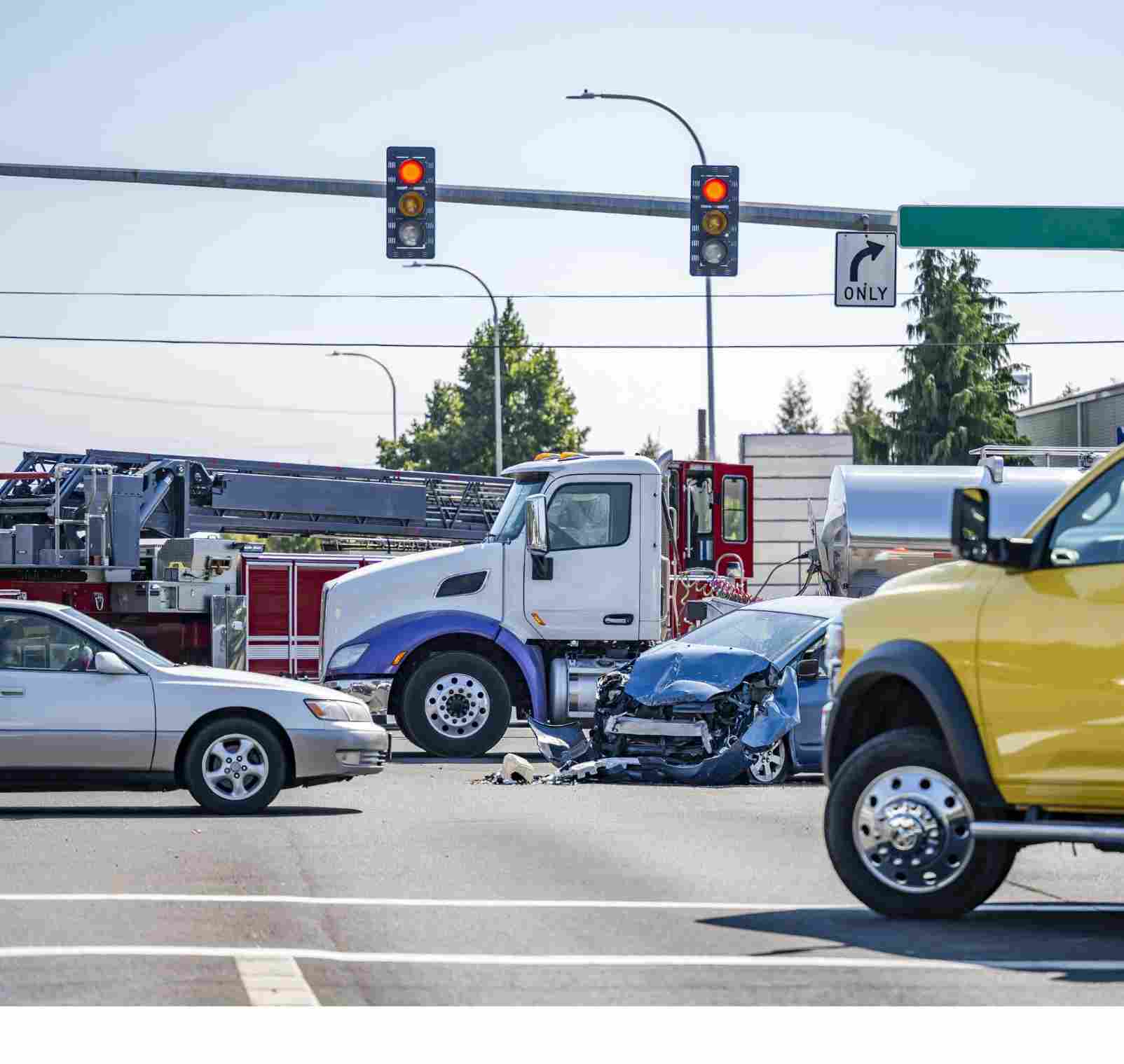 Damaged cars after a car accident crash involving a big rig semi truck with semi trailer at a city street crossroad intersection with traffic light and rescue services to help the injured