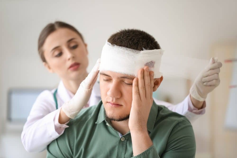 Man Holding His Bandaged Head In Pain